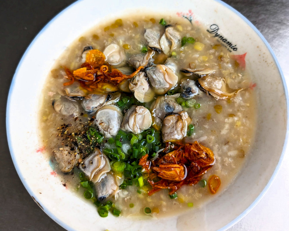 The fresh herbs, crispy shallots, and a hint of black pepper add layers of flavor, making each spoonful of clam porridge a delightful experience 
